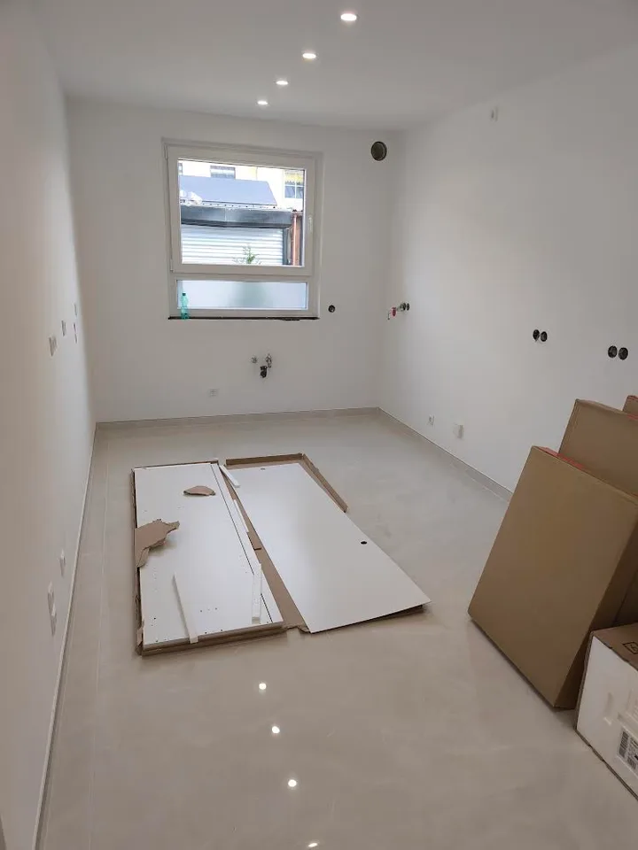 Raum vor der Küchenmontage mit vorbereiteten Anschlüssen und Platz für die Spüle unter dem Fenster